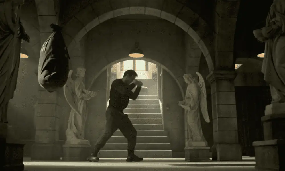 Matt practices boxing in the church basement, under an arched ceiling, flanked by two angel statues.