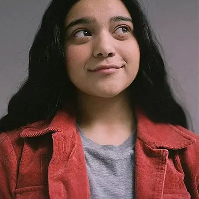 Young Pakistani girl with Black hair wearing a grey tee and red jacket.