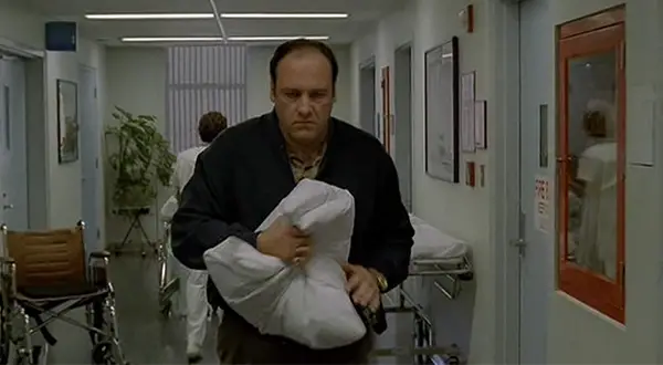 Tony Soprano carrying a pillow with malicious intent.