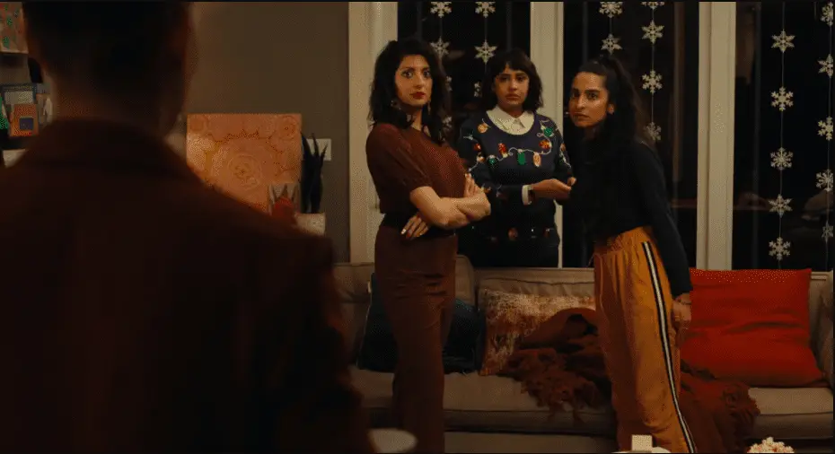 Three Pakistani sisters looking at character whose back is facing to the camera in syed family xmas eve game night