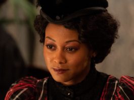 A dark-skinned Black woman with curly hair and a Black hat (Shanice Banton as Violet Hart)