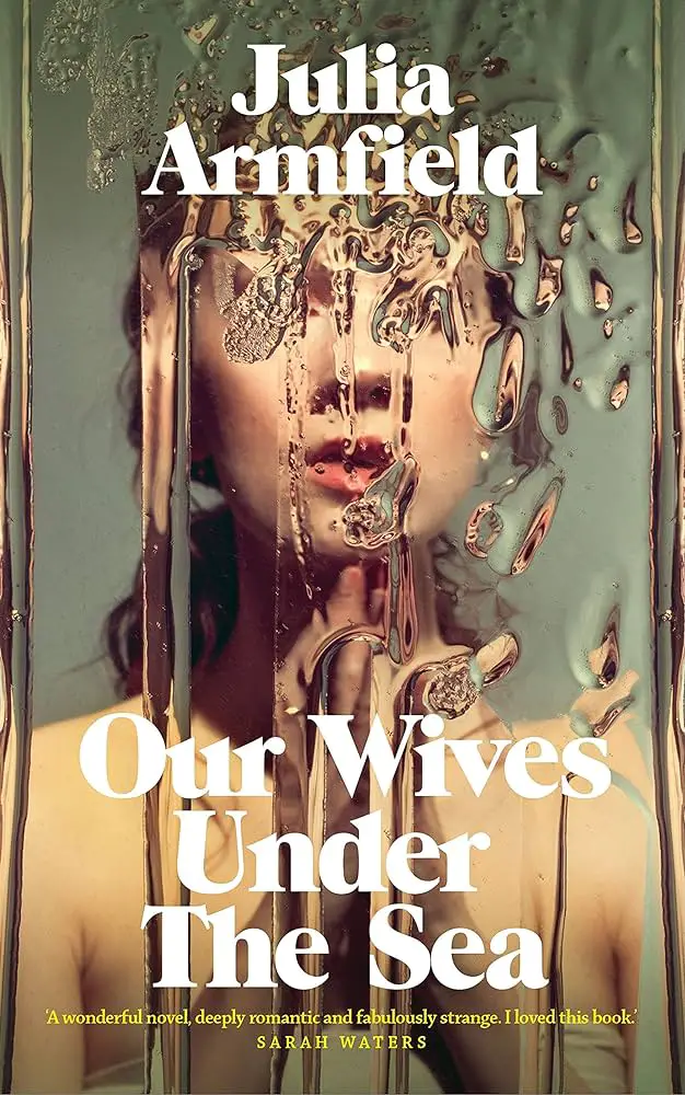 Cover for Our Wives Under The Sea by Julia Armfield which shows a woman's face distorted by glass covered with water. The bottom has a commendation from Sarah Waters reading "A wonderful novel, deeply romantic and fabulously strange. I loved this book"