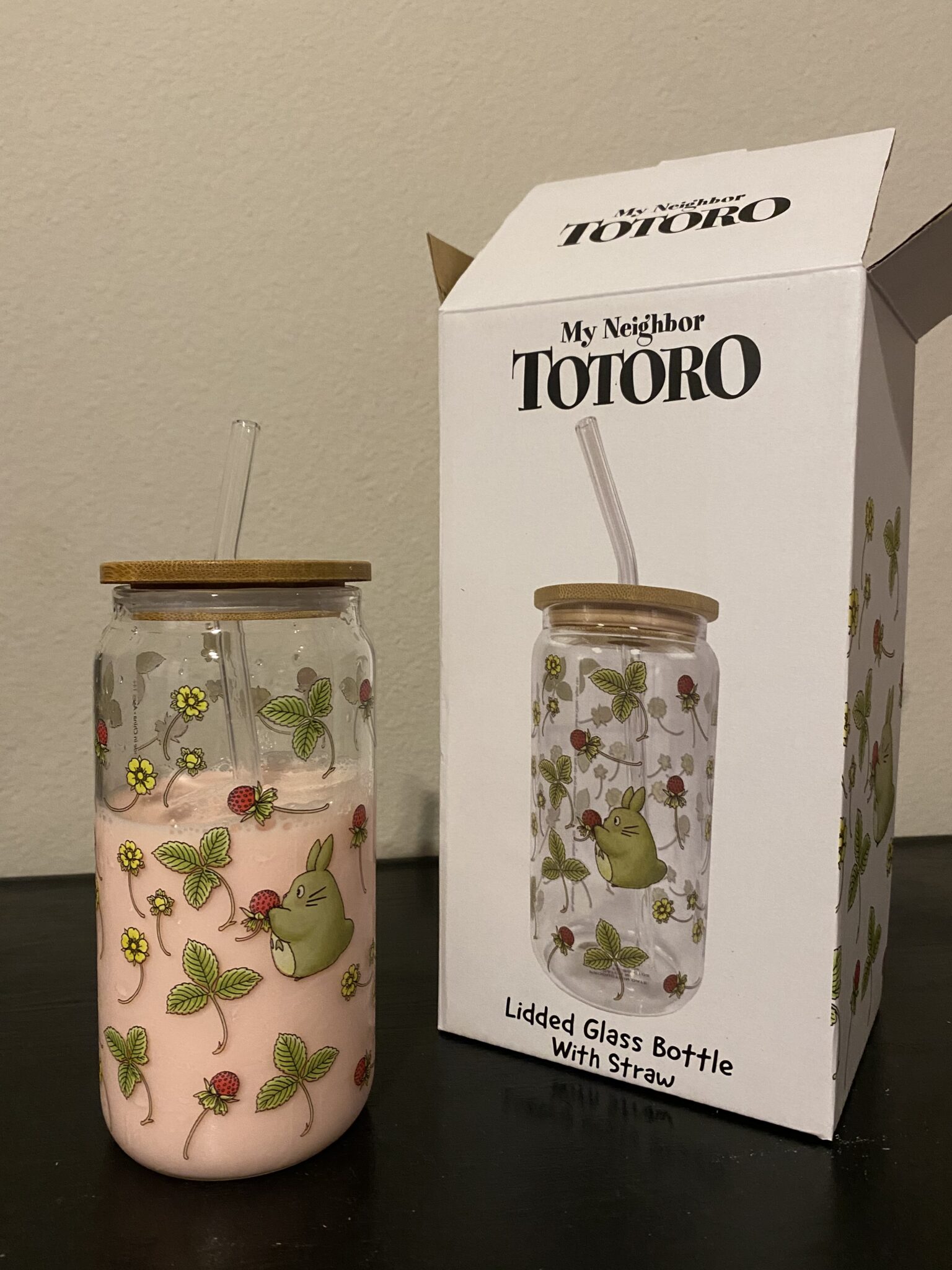 a glass cup with pink liquid next to a box showing the cup in its packaging