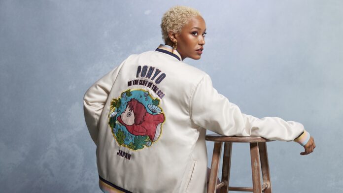 Black person with short hair wearing a cardigan that has Ponyo on the back from Boxlunch