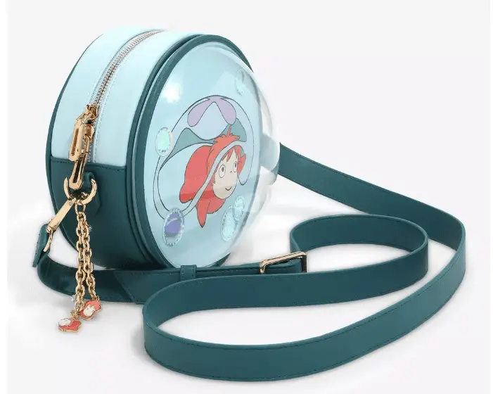 angled photo of a blue and teal circle crossbody bag with ponyo on the front and a plastic dome