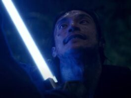A blue lightsaber lights Qimir's face from The Acolyte