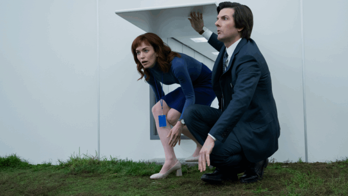 Helena and Mark crouched together as they enter a white room with grass. Apple+ Severance