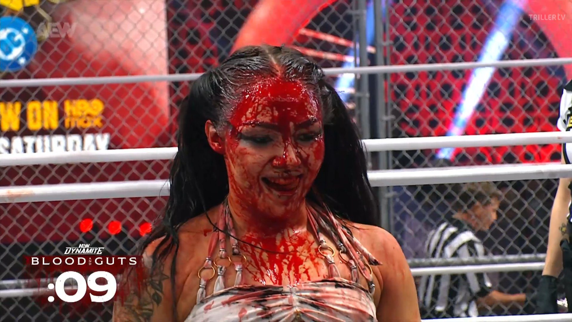 Skye Blue, a young white woman with dark hair pulled back in pigtails, grins deviously. Her face is covered in her own blood.