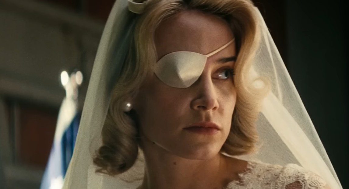 A closeup of Stephanie wearing a bridal gown, veil, and matching white satin eyepatch.